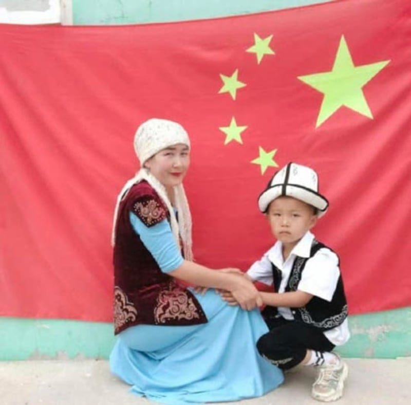 伊犁尼勒克县一哈萨克族妇女与孩子在中国旗前拍照。(乔龙提供)