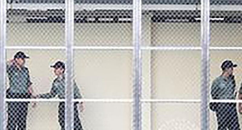 2020 年港版《国安法》通过后,不少倡议监所人权、支持被捕者家属的公民团体被取消或解散,惩教署职员招募培训流程中亦新增《基本法及香港国安法》测试。图为关押候审疑犯、待分发执行判决囚犯的荔枝角收押所内的警卫。(摄影/REUTERS/Bobby Yip/达志影像)