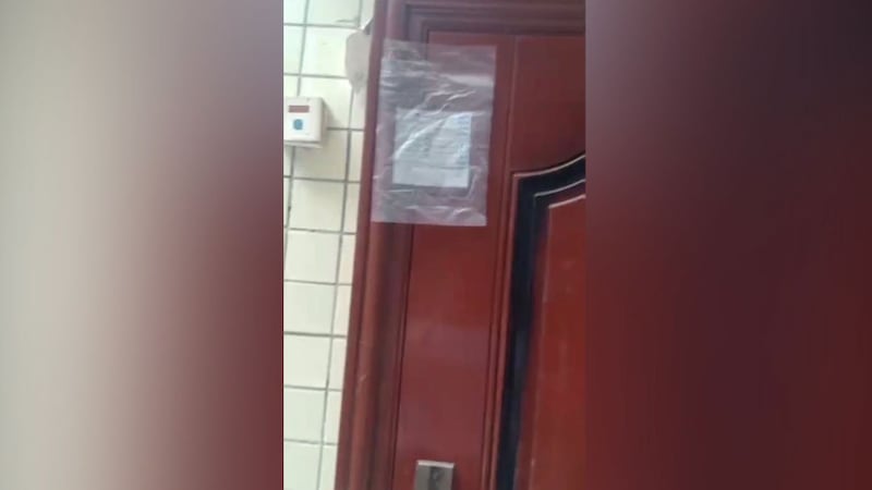 谢文飞的住所大门,贴着一个写有“物证封存”的塑料袋。(志愿者提供/记者乔龙)