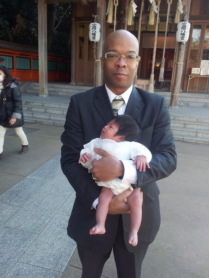 2013年,小威尔斯与刚出生不久的女儿贾丝明在日本横滨的一座神社前合影。(威尔斯一家提供)