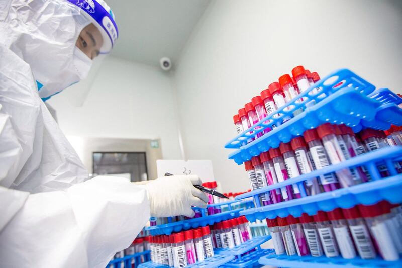 2022 年 4 月 27 日,一名身穿个人防护装备 (PPE) 的实验室技术人员在中国东部江苏省海安市的 Covid-19 测试实验室工作。(法新社)