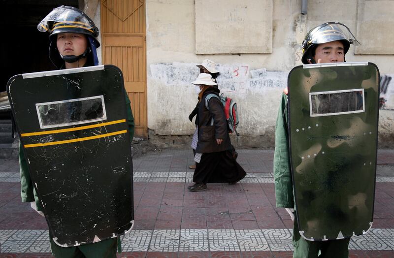 Tibetan women walk past Chinese paramilitary police on a street in Lhasa, Tibet Autonomous Region, March 27, 2008.