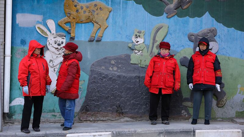 戴着红袖章的老年志愿者,在北京市中心的街道路旁值班。(路透社)