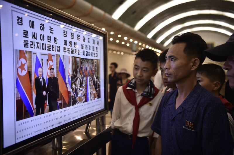 People look at the Rodong Sinmun newspaper showing the news on the visit by Russian President Vladimir Putin, in the Kaeson Station of the Pyongyang Metro in Pyongyang on June 20, 2024.