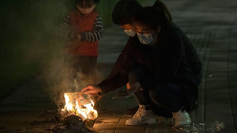 图为,2020年4月4日,湖北省武汉市一家人在街上为其亲人烧纸祭。(美联社)