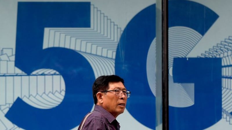 资料图片:2019年6月6日,一名男子走过在北京购物区展出的5G网络广告。(美联社)