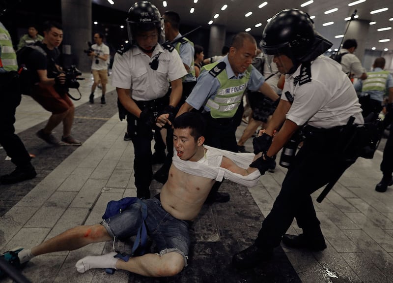 2019年6月10日凌晨12点,一批戴上口罩和面罩的示威者手挽手闯进香港立法会示威区,推倒铁马,推向警察防线。抗议者与警察发生冲突。(美联社)