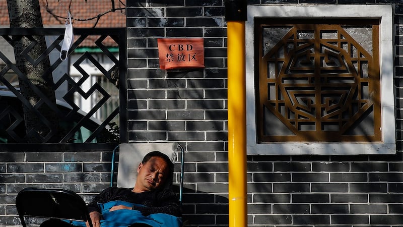 虽然武汉城疫情未解除,但四川和安徽两个省政府却忙着“摘口罩”。图为,2020年3月11日,一名男子的口罩挂在北京中央商务区的树枝上。(美联社)