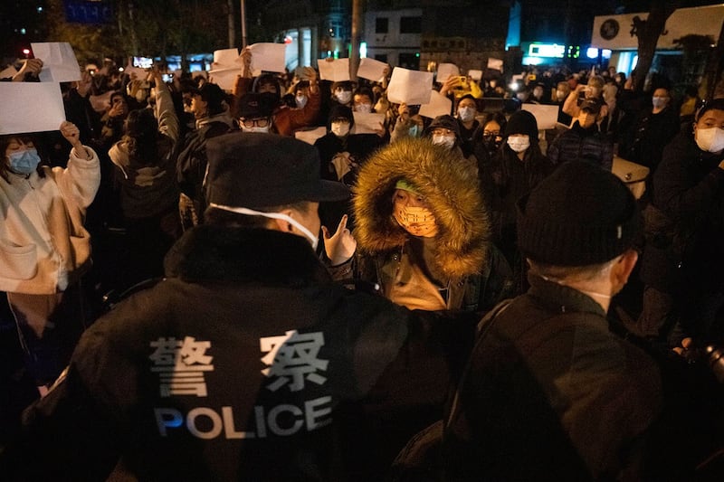 2022年11月27日,中国警察在北京与举着白纸的抗议者对峙。(美联社)
