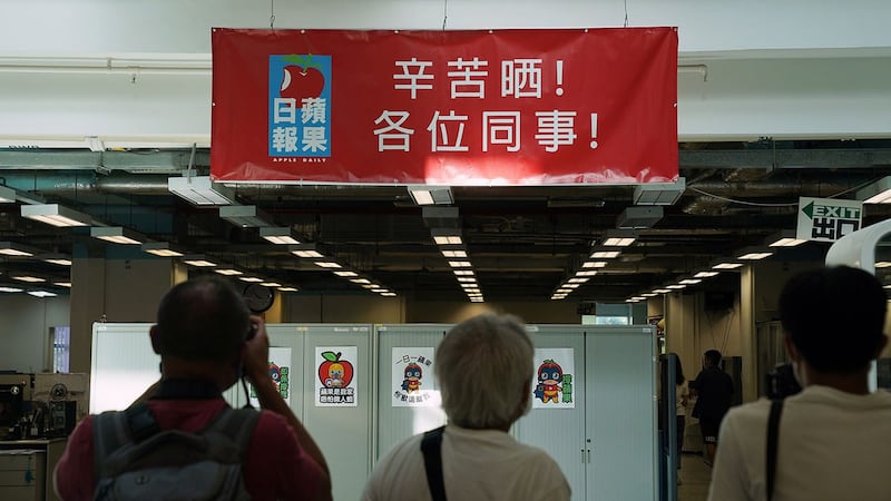 2021 年 6 月 17 日,香港警方突袭新闻编辑室后,媒体成员在《苹果日报》办公室的横幅前拍照,横幅上写着“辛苦晒!各位同事!” 。(路透社)