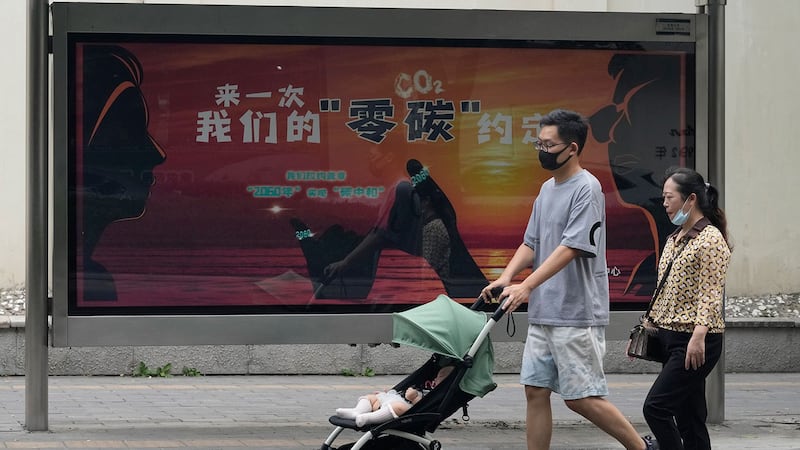 2021 年 8 月 30 ,北京一街道上居民经过政府宣传位,上面写着“我们的碳零协议” 。(美联社)