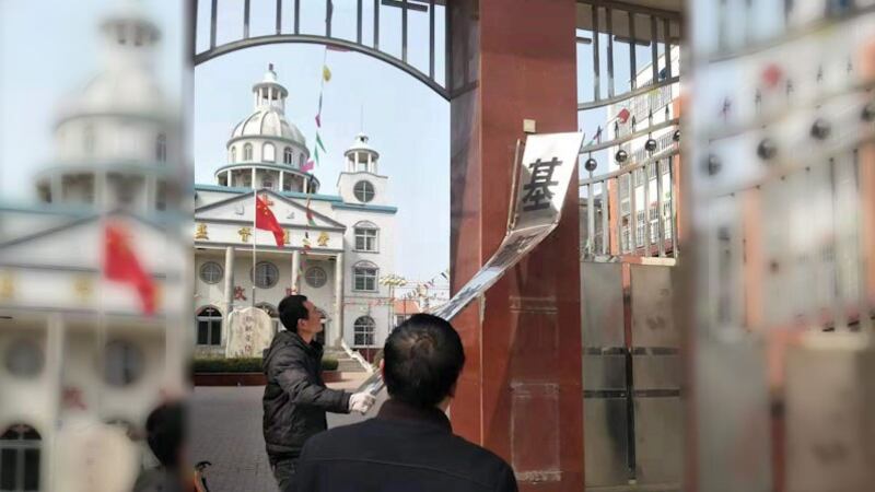 政府方人员正在拆除李军才带领的教会大门口牌子。(志愿者提供/记者乔龙)