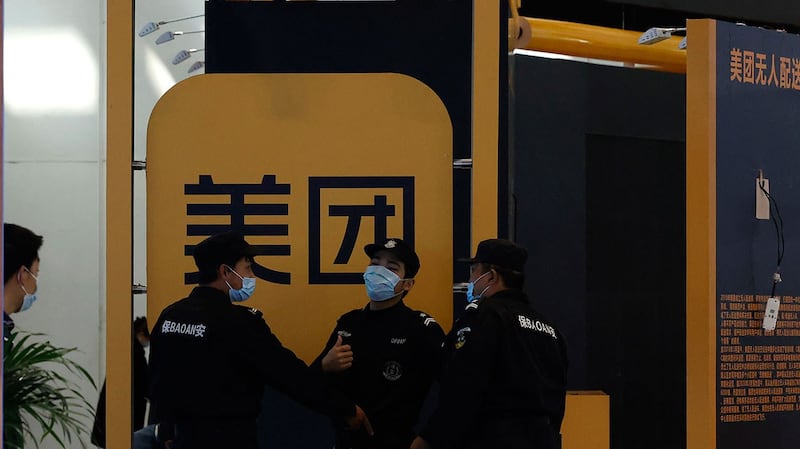 2021 年 4 月 30 日,在北京举行的互联网技术博览会上,保安人员在美团标志附近。 (美联社)