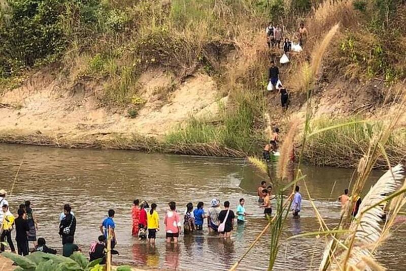 Civilians fleeing fighting between the Myanmar military and the Karen National Union cross a river in eastern Myanmar's Kayin state, along the Thai-Myanmar border, Dec. 25, 2021. Credit: AFP
