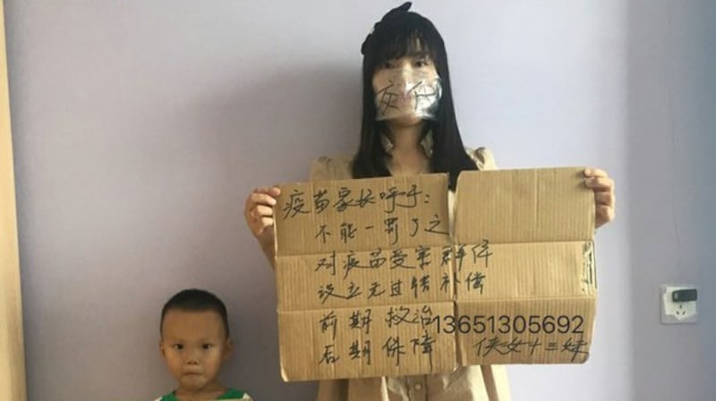 问题疫苗受害儿童的家长何方美举牌抗议(志愿者提供/记者乔龙)