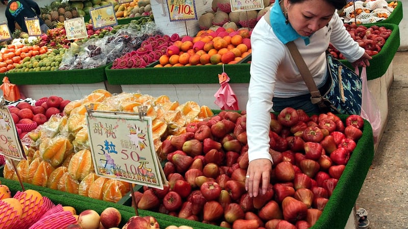 一名妇女在台北的当地水果市场挑选台湾热带水果。（美联社）