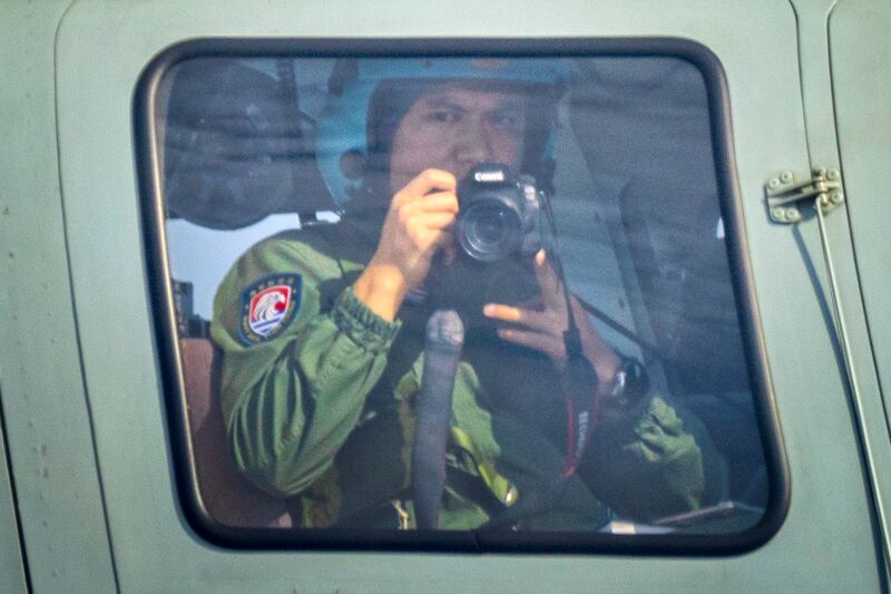 Chinese Navy personnel takes pictures from aboard a helicopter flying close to a Philippine Bureau of Fisheries and Aquatic Resources plane above Scarborough Shoal on February 18, 2025 in the South China Sea.