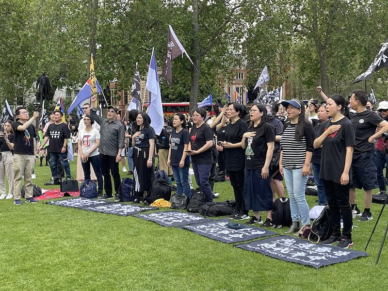 近千名港人酷热下在英国国会大楼前“如水再聚”,无惧港府恐吓,高唱《愿荣光归香港》。不少参加者颂唱时手放胸前,神情凝重。 (吕熙摄)